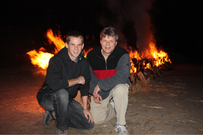 Rob Fore and his son Tony Fore crouched in front of the firewalk fire at night, December 2008